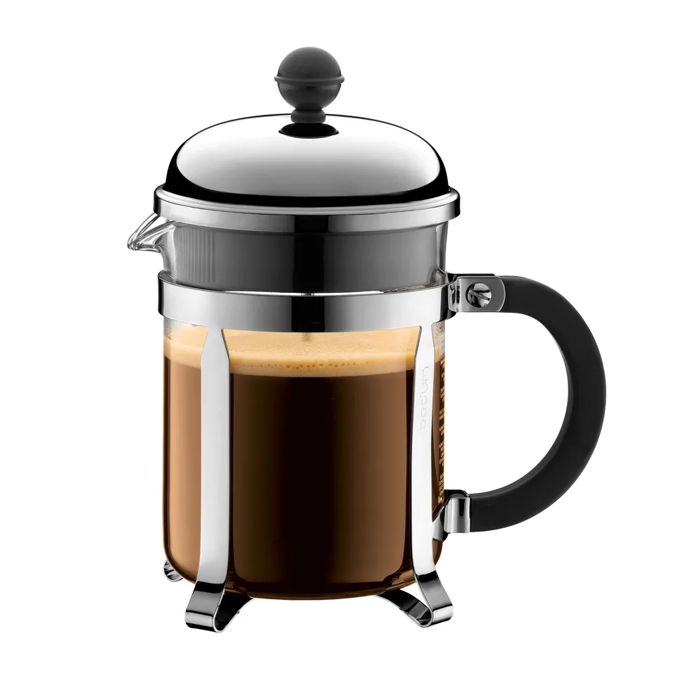 Stempelkande med glaskolbe fuld af mørk kaffe i et kromstel på fire fødder, kromlåg med sort kugleknop og stempelstang, og et sort håndtag i siden, på hvid bund