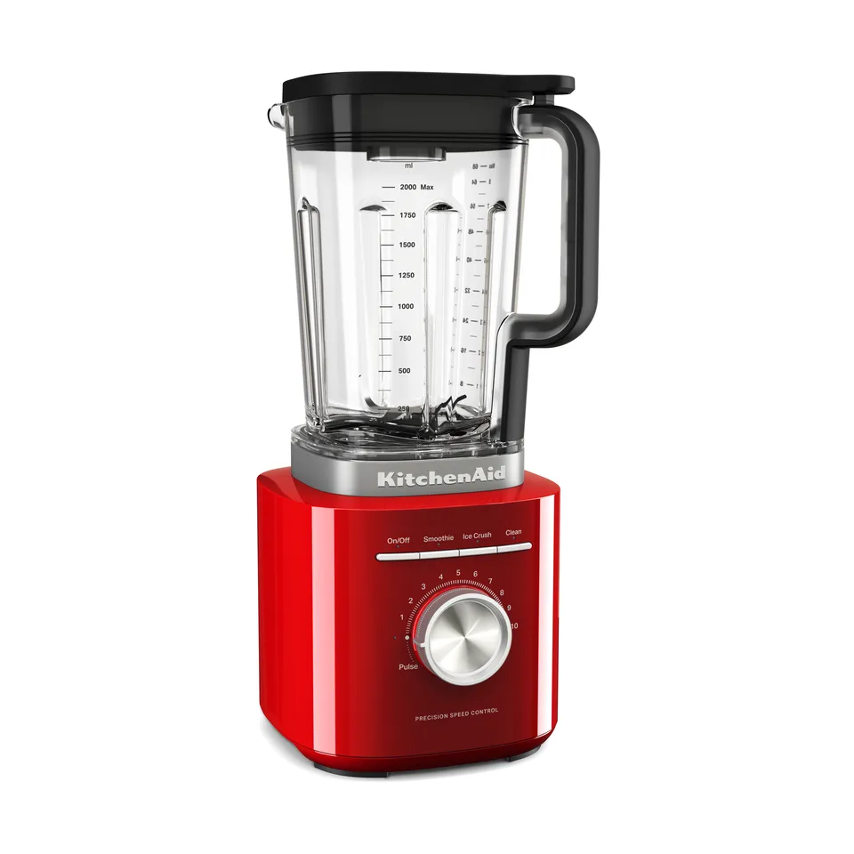 Rød blender på hvid bund med kantet motorhus, stor rund metalknap foran og en klar kande med litermål og sort hank