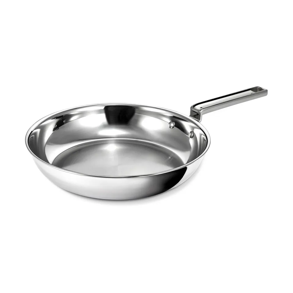 Blank stegepande i poleret rustfrit stål med langt fladt stålhåndtag, set skråt ovenfra på hvid bund