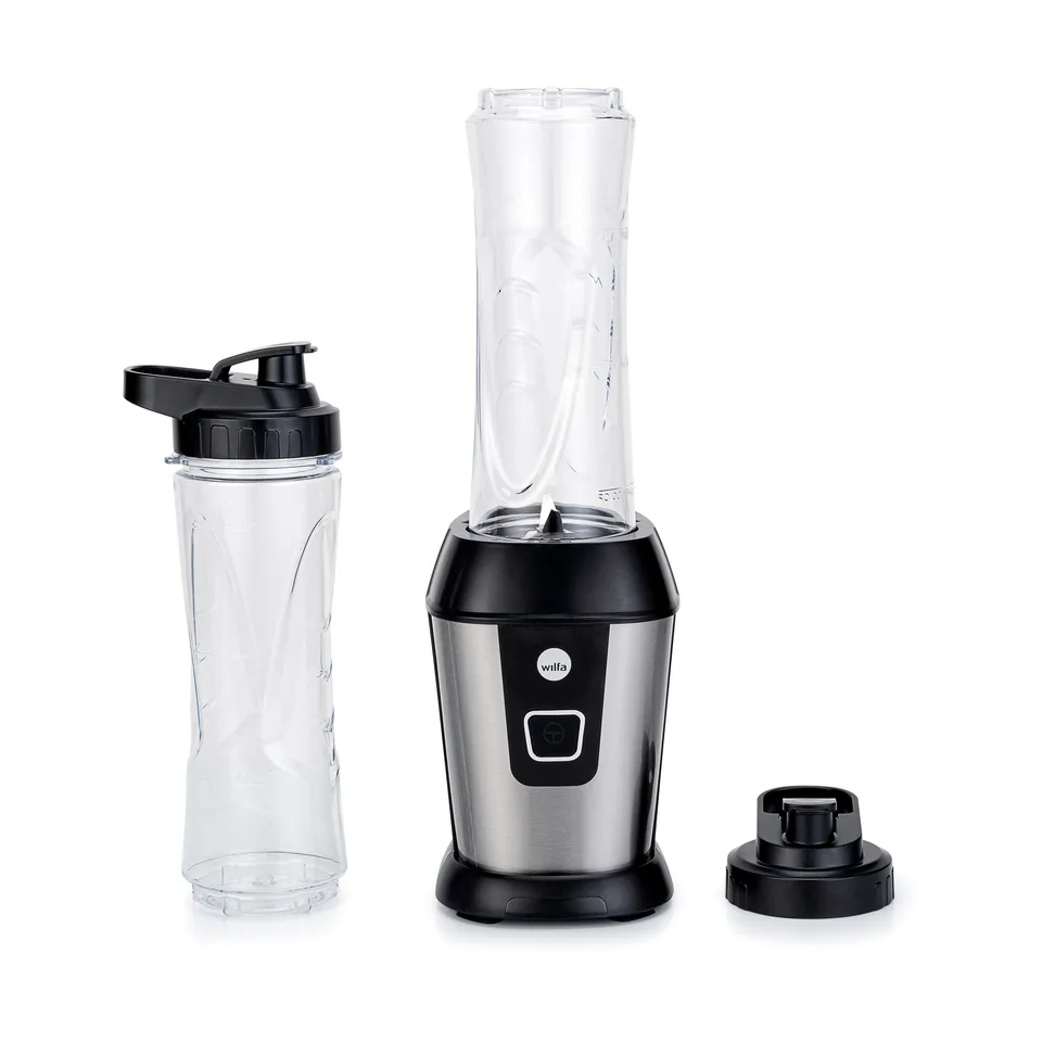 Lille blender i stål og sort med en høj klar beholder sat på soklen, en ekstra klar flaske med sort drikkelåg ved siden af og en sort skruedel med kniv, på hvid bund