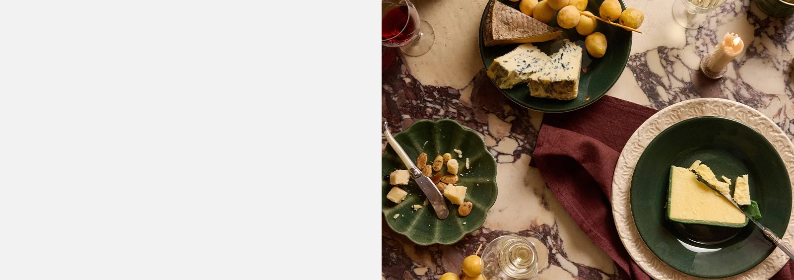 Overheadbillede af et marmorbord med luksuriøst ostefad, vinglas og et tændt stearinlys.