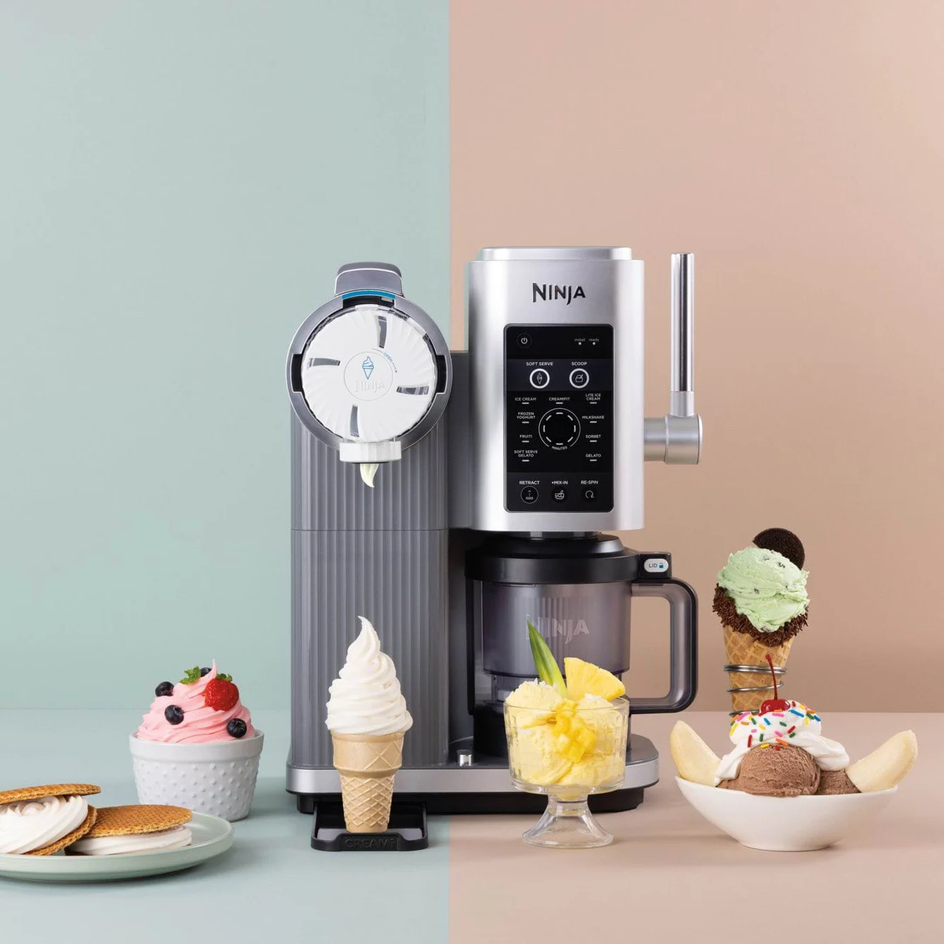 En sølvfarvet softice-maskine omgivet af forskellige frosne lækkerier som softice-vafler, sundaes og sorbet.