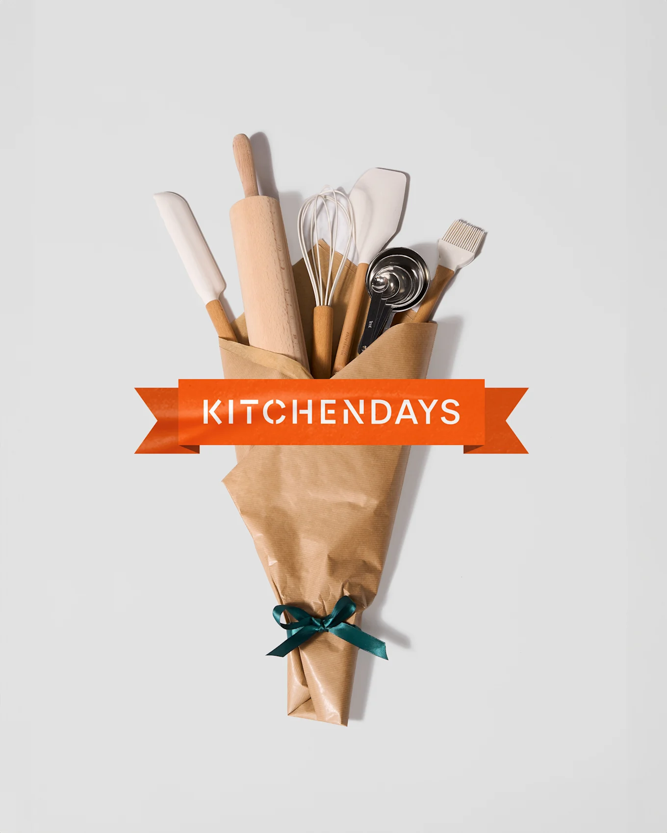 En buket køkkenredskaber pakket i brunt papir med grønt bånd og orange banner: 'KITCHENDAYS'.